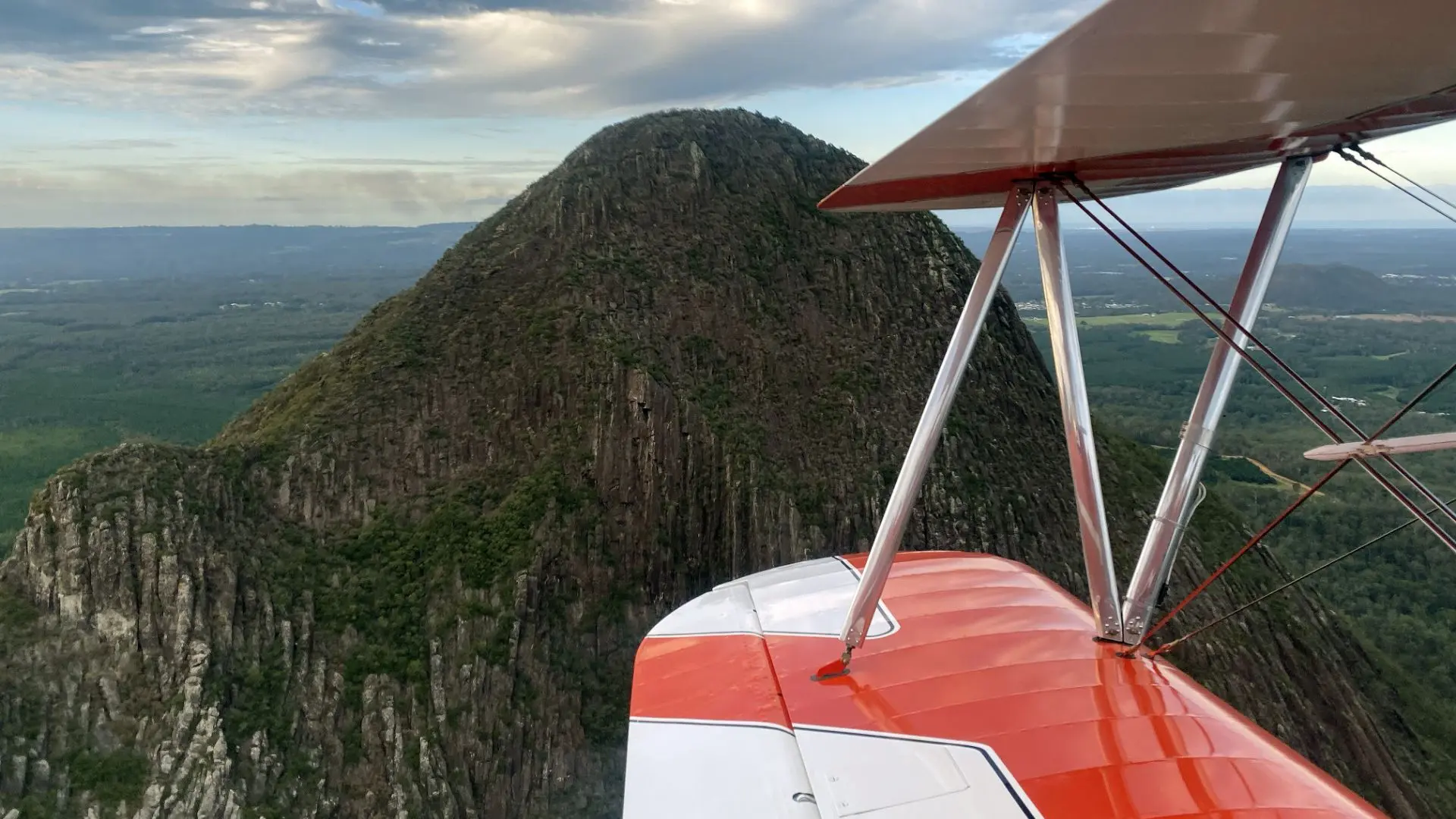 A view of the Glasshouse Mountains from the pilot seat of a Stearman plane